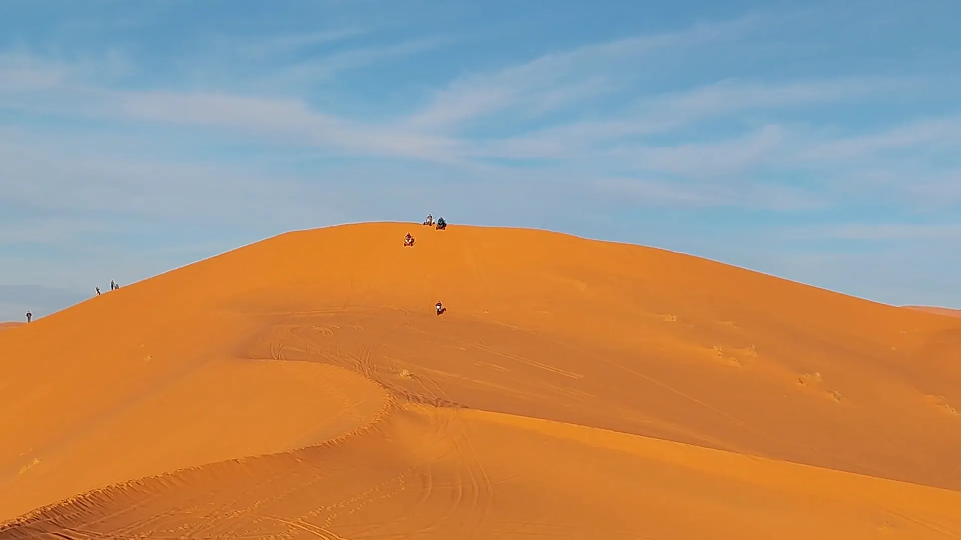 Travellers walking along a dune ridge in the Sahara